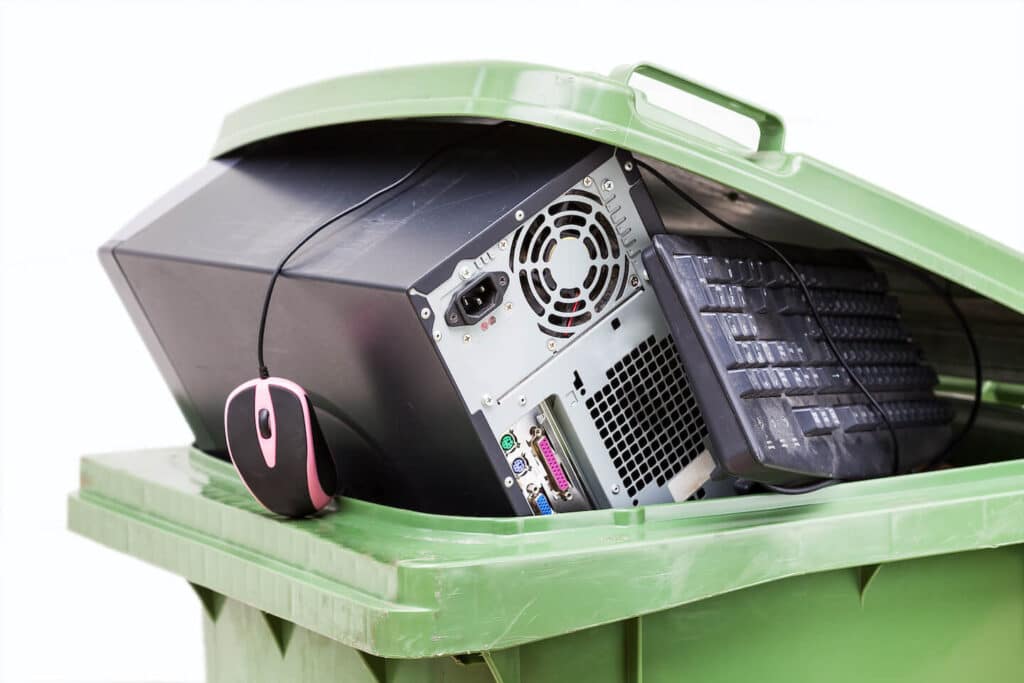 Ordinateur, clavier et souris dans une poubelle verte