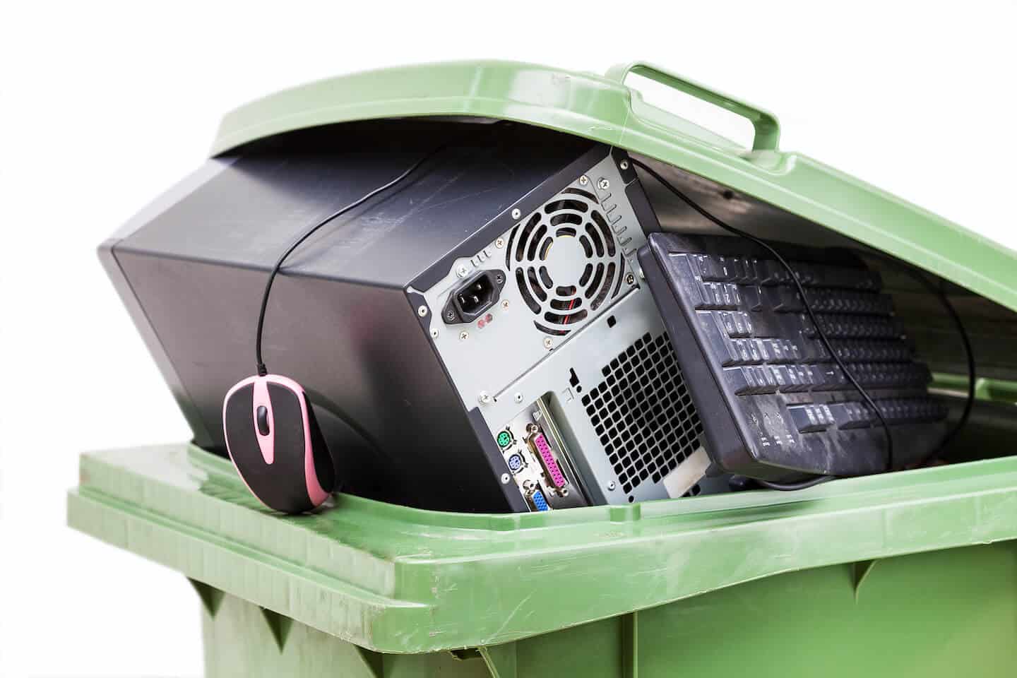 Ordinateur, clavier et souris dans une poubelle verte